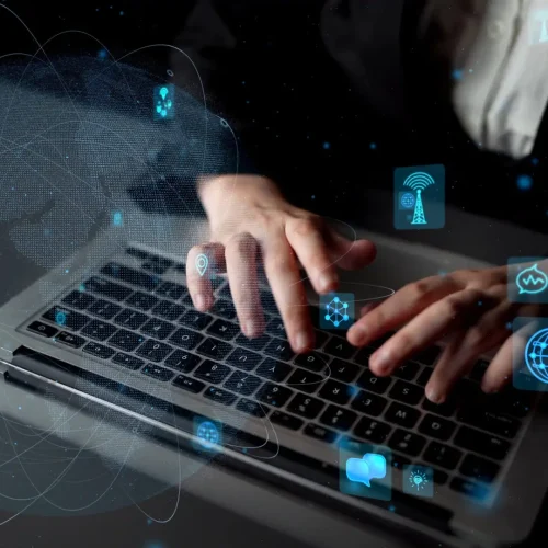 A close-up view of hands typing on a laptop, surrounded by futuristic icons representing digital communication and technology innovation in a modern workspace setting.